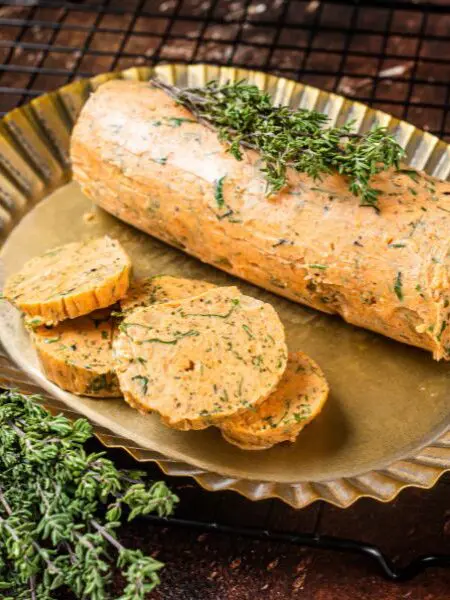 Tomatenbutter Rezept, rund geformte Tomatenbutter in einer goldenen Servierschale mit Kräutern als Dekoration